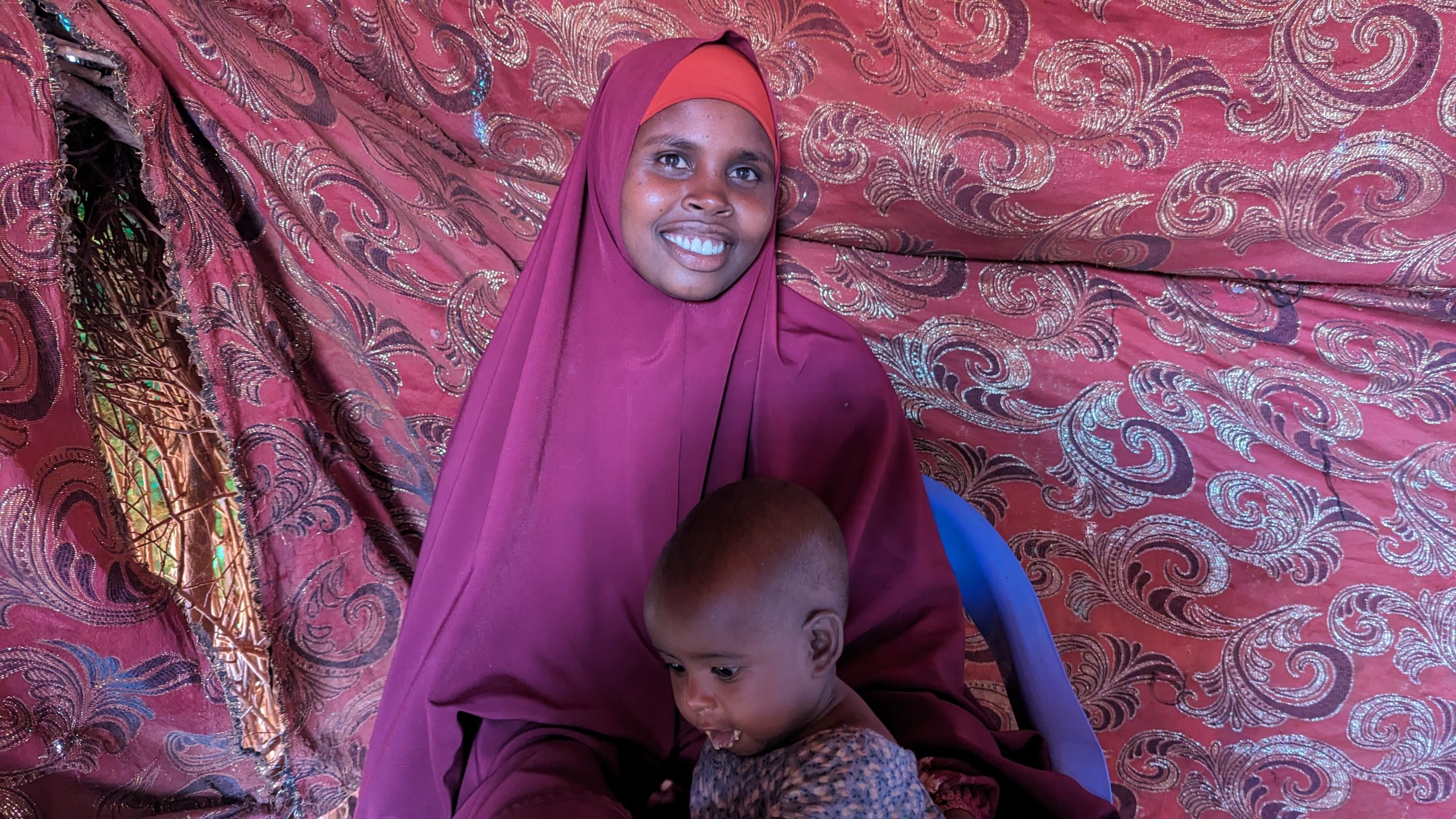 Falastin enjoys peanut paste given to her at the outreach site. Her mother is happy with the progress her daughter is making following weeks of nutrition treatment. Photo by Mohamed Adan Maalim, ACF Communication and Advocacy Officer.